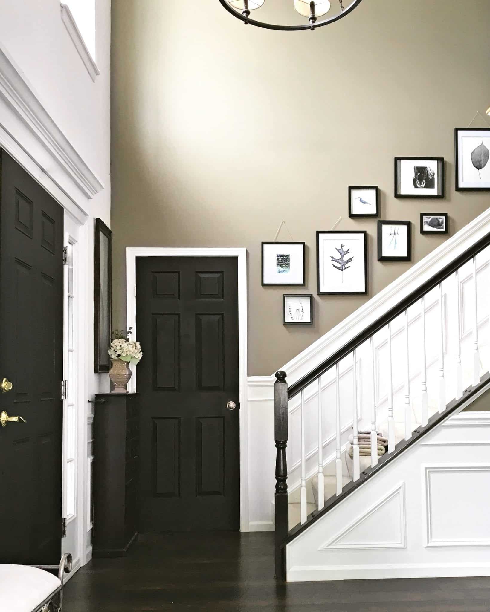 Foyer with wainscoting black doors gallery wall upstairs