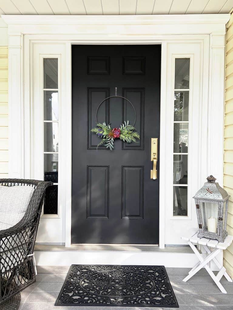 front porch with black door with modern wreath
