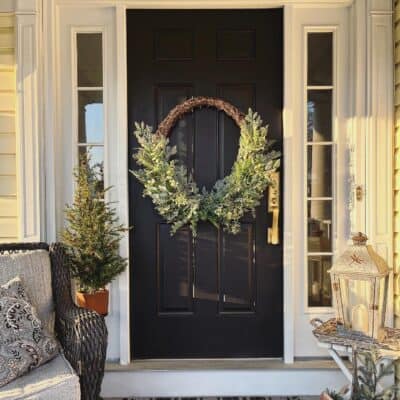 Black door with winter porch decor and plaid rug